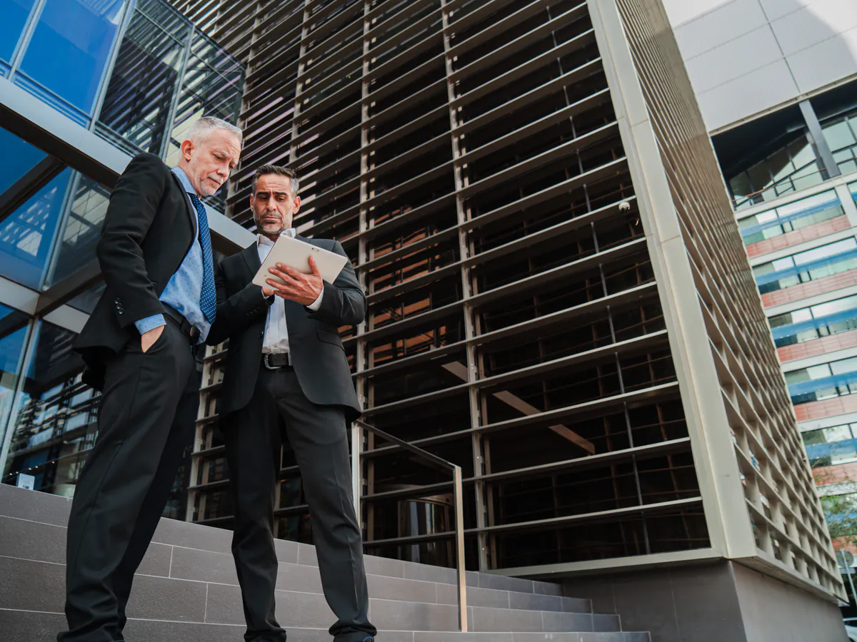 Ejecutivos revisan un desarrollo frente a un edificio moderno dentro de una infraestructura digital para real estate.
